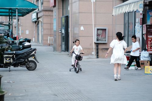 Free A young girl joyfully rides a bicycle on an outdoor urban street setting. Stock Photo
