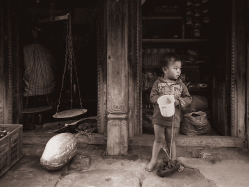 Free A young child plays with a toy in a rustic, monochrome setting. Stock Photo