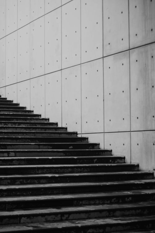 Free Black and white image of an urban staircase beside a concrete wall in a city setting. Stock Photo