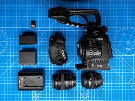 Flat lay of Canon cinema camera and gear on blueprint for filmmaking.