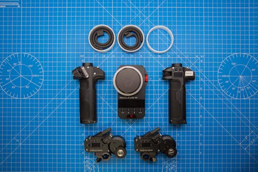 Flat lay of videography equipment on a blue grid surface, showcasing focus gears and handles.