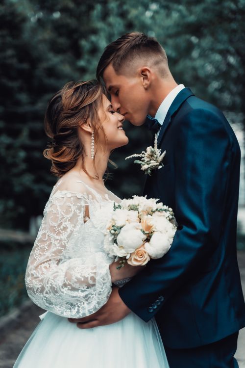Free Bride and groom embracing with eyes closed and smiling outdoors. Stock Photo