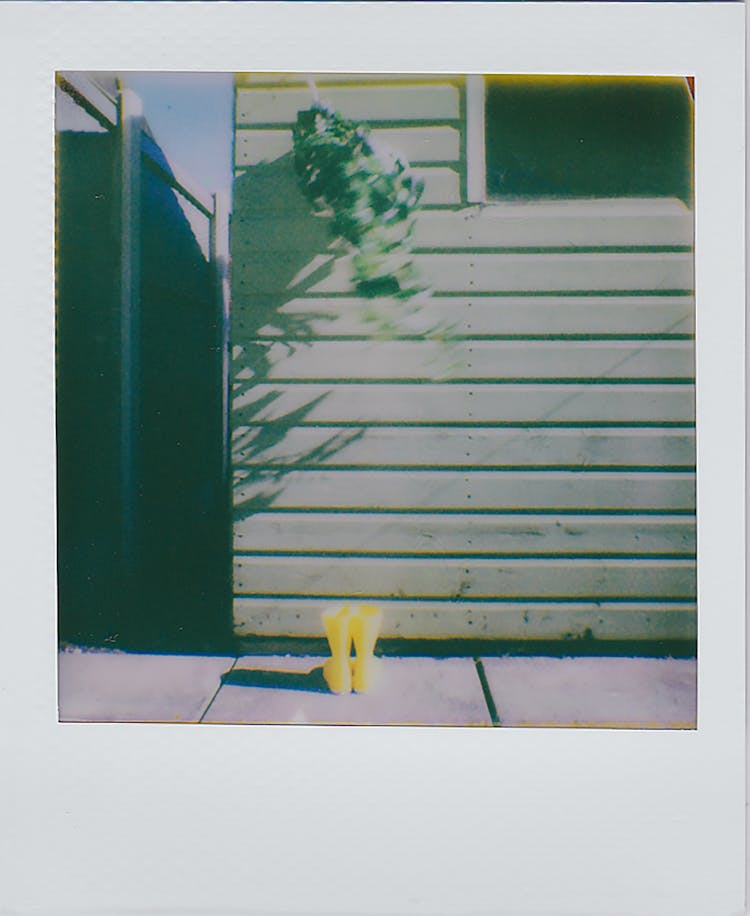 Polaroid Shot Of Yellow Rain Boots Near House