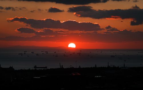 Free Stunning sunset over the ocean with silhouetted boats and scenic clouds, creating a dramatic horizon view. Stock Photo