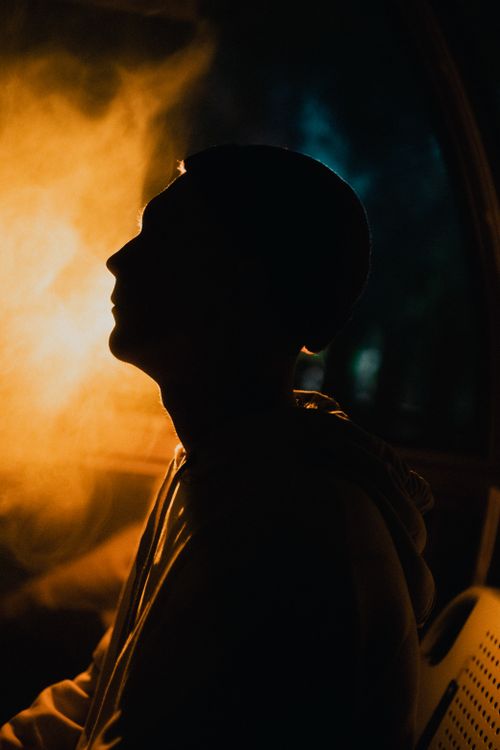 Free Backlit silhouette of a man with dramatic warm lighting, creating a mysterious mood. Stock Photo