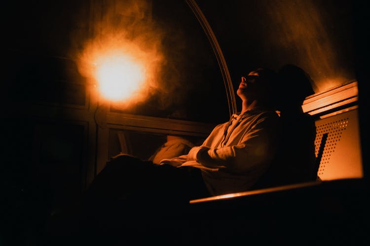 Man Sitting On Bench In Dark Room With Light