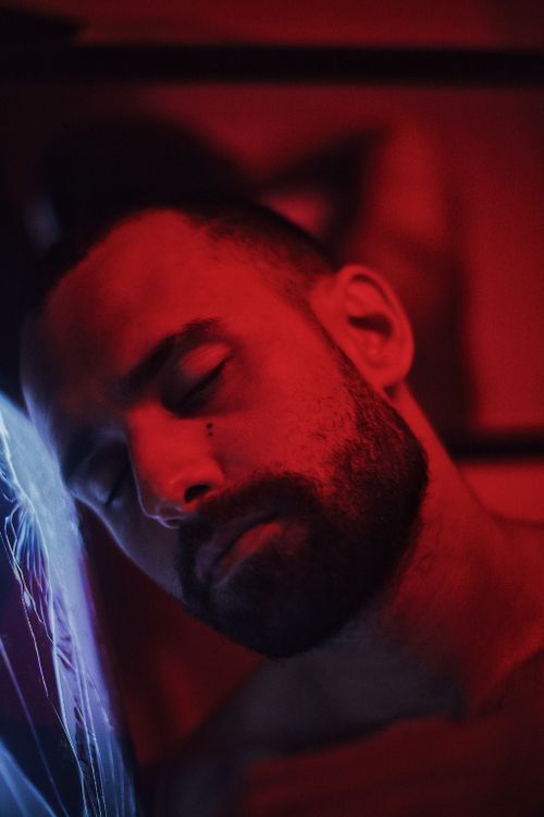 Free Pensive and emotional portrait of a bearded man under red lighting, reflecting solitude. Stock Photo