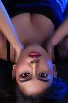 Artistic portrait of a woman lying down showcasing bold makeup and elegance.