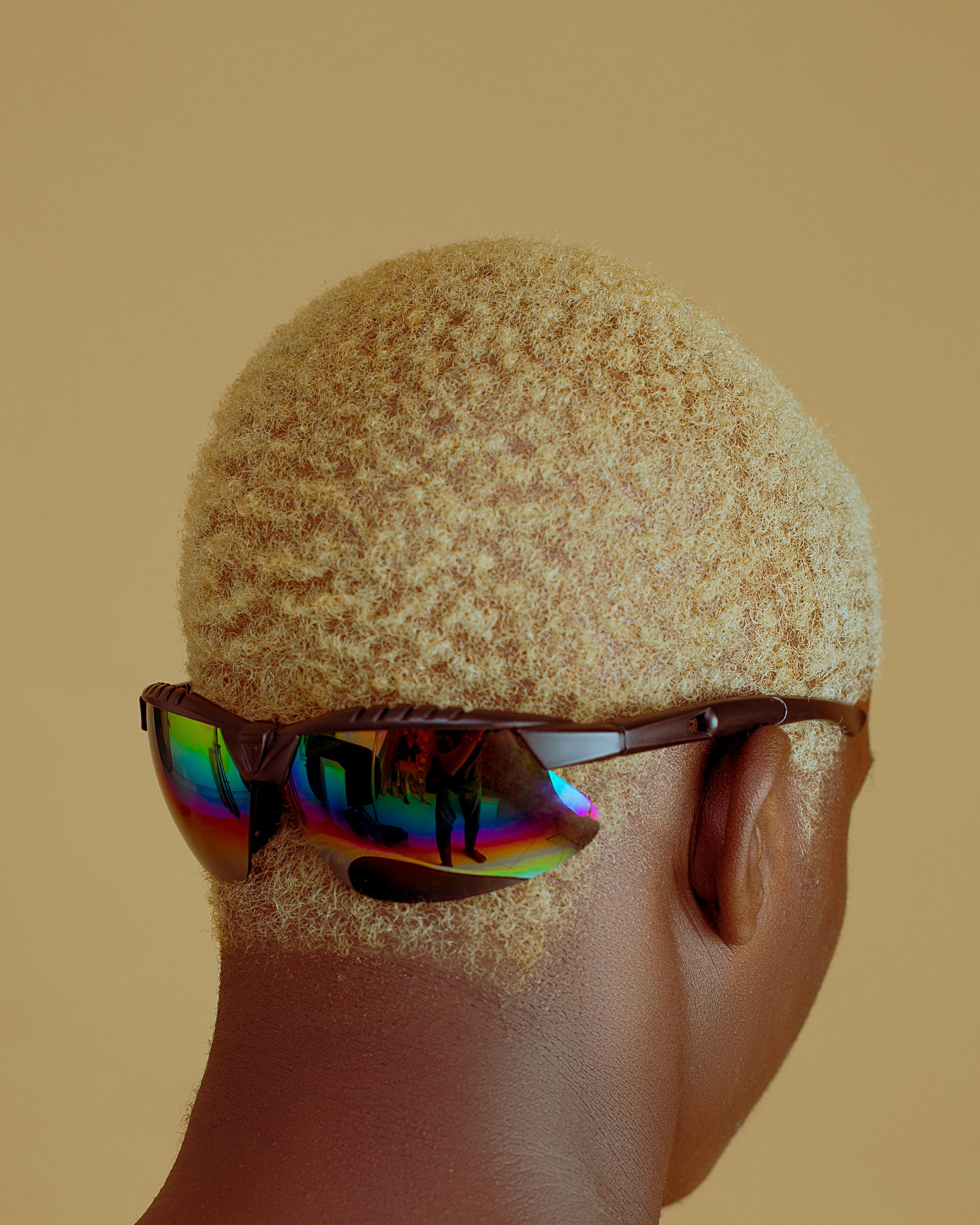 Close-up back view of a person with sunglasses against a yellow background, showcasing fashion style.