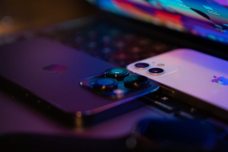 Close-up image of two modern smartphones placed on a laptop keyboard, highlighting technology design.