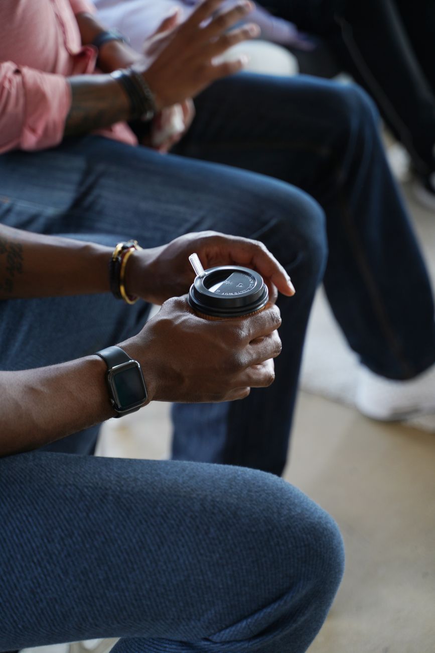 Close-up of hands holding a disposable coffee cup in a casual indoor setting.. close, hands, holding