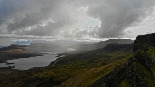 Free Stunning overcast landscape of Portree, Isle of Skye, Scotland with dramatic clouds over rolling hills and water. Stock Photo