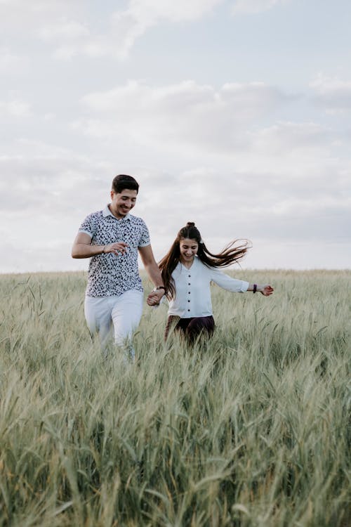 Couple Running through Field Holding Hands