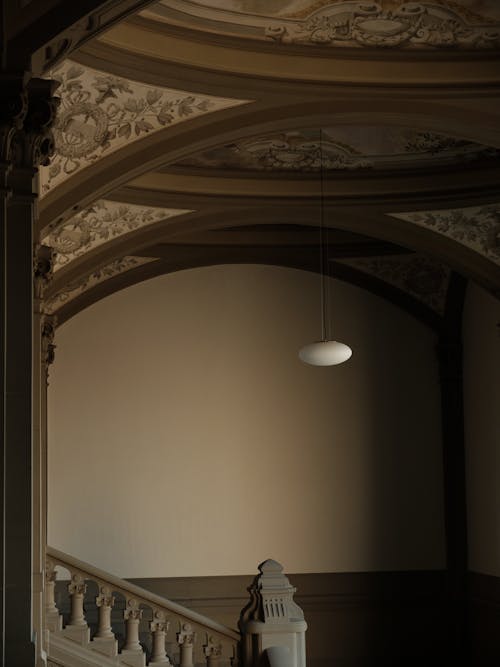 A Lamp in a Floral Arch Shaped Ceiling Near a Staircase