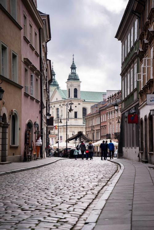 Free Cobblestone street in Warsaw's Old Town with historic architecture and St. Anne's Church. Stock Photo
