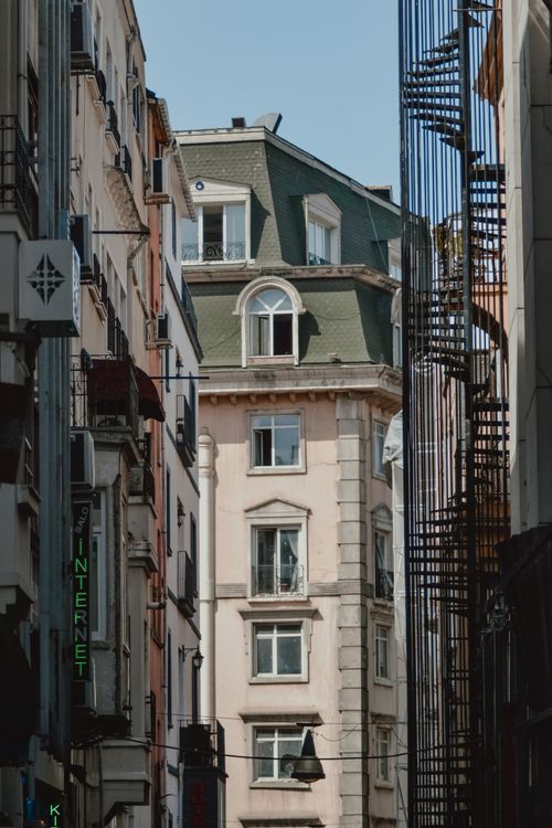 Free Vertical view of a city alley featuring classic European architecture with fire escapes. Stock Photo