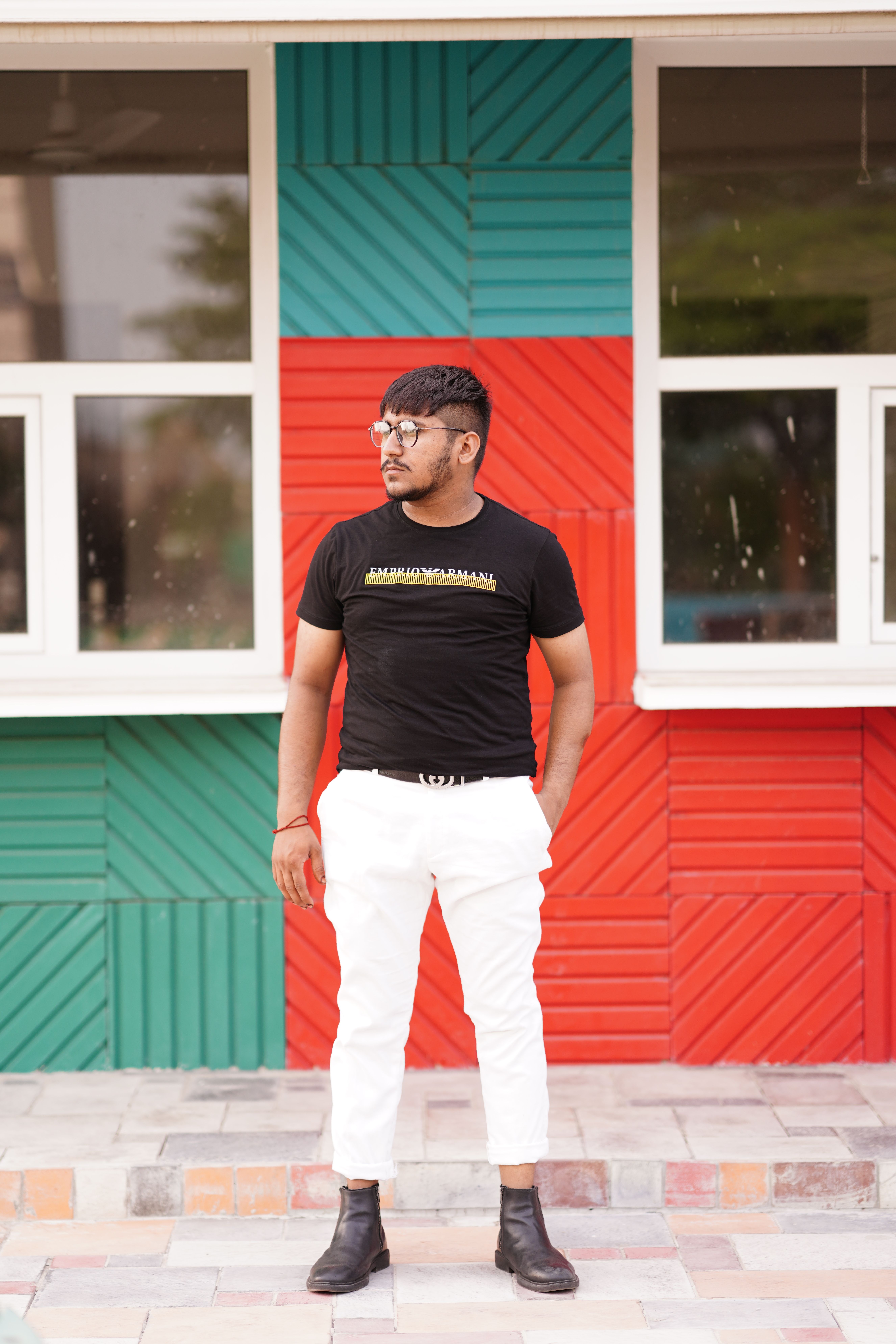 Young man in black shirt and white pants posing confidently outdoors in Lahore.