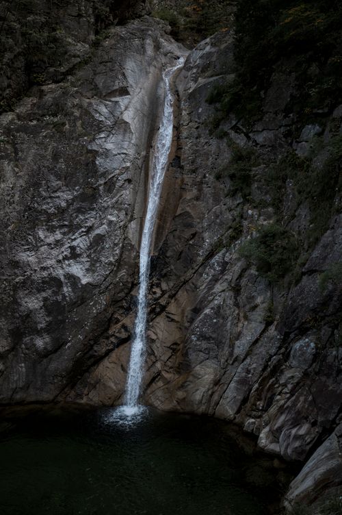 Free A breathtaking waterfall cascades over rugged rocks into a tranquil pond, a photographer's paradise. Stock Photo