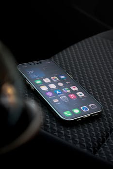 Close-up view of a smartphone displaying apps on a car seat highlighting connectivity.