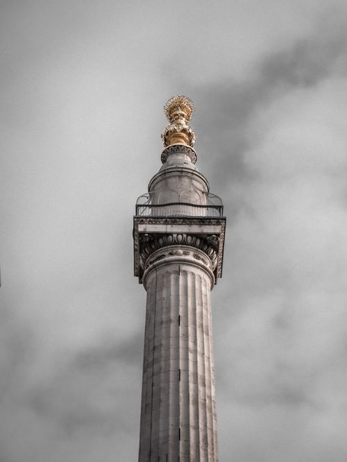 Free A dramatic low-angle shot of the Monument to the Great Fire of London against a cloudy sky. Stock Photo