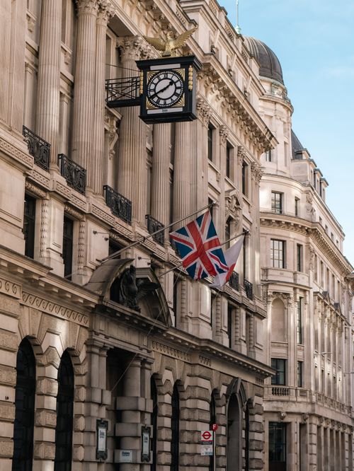 Free Classic architecture in the UK featuring a clock and Union Jack flag on a historic building facade. Stock Photo