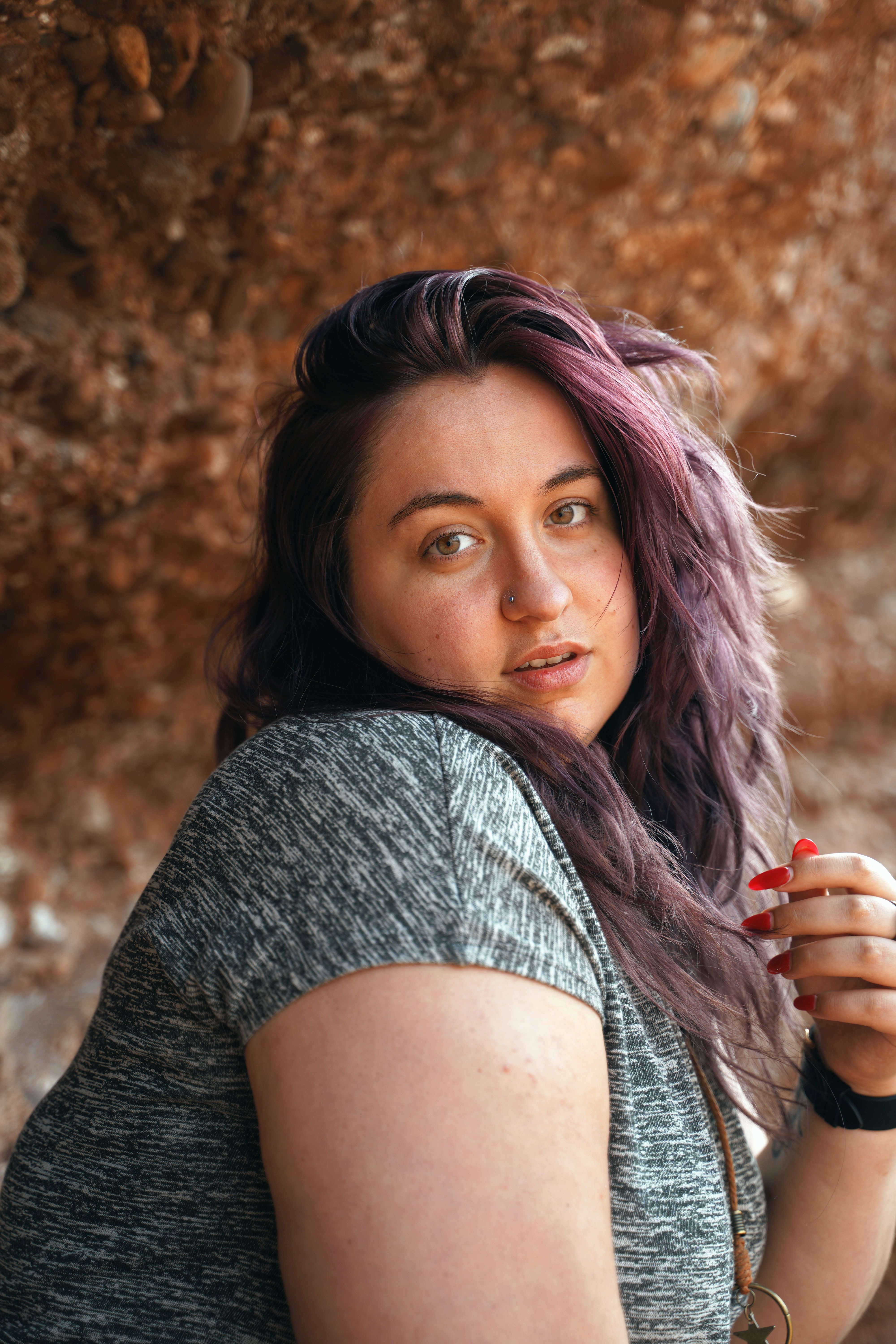 Elegant portrait of a woman with purple hair and nose piercing, outdoors.