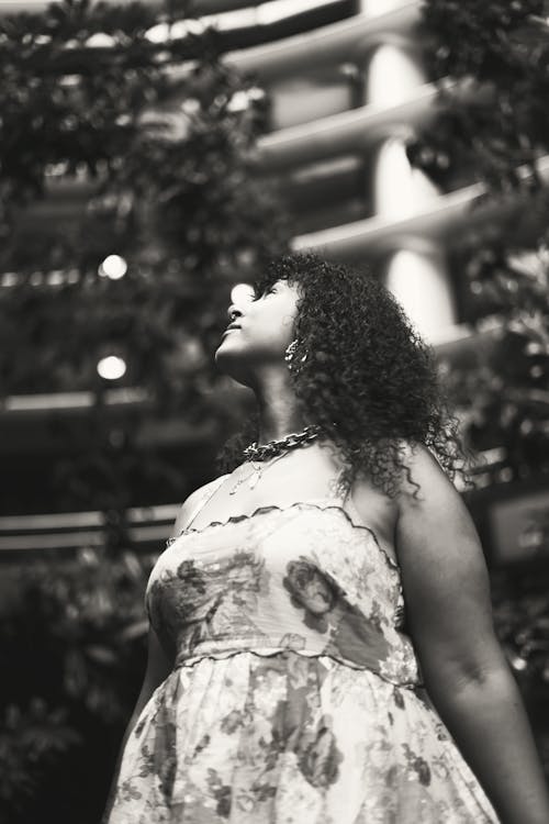 A Grayscale Photo of a Woman in Printed Dress Looking Up