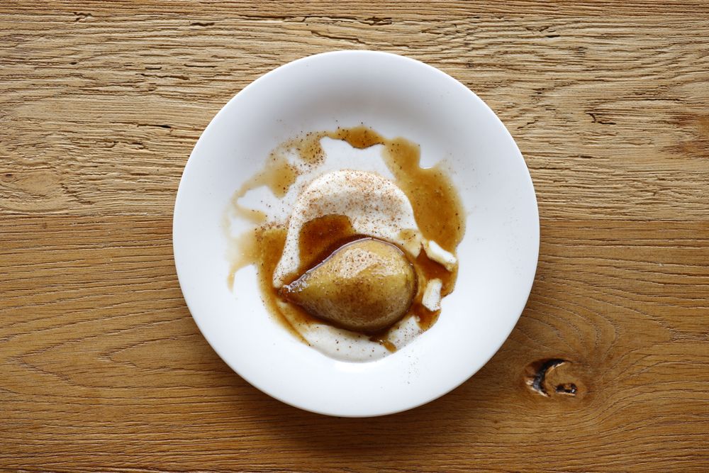 Poire pochée nappée de caramel dans une assiette blanche