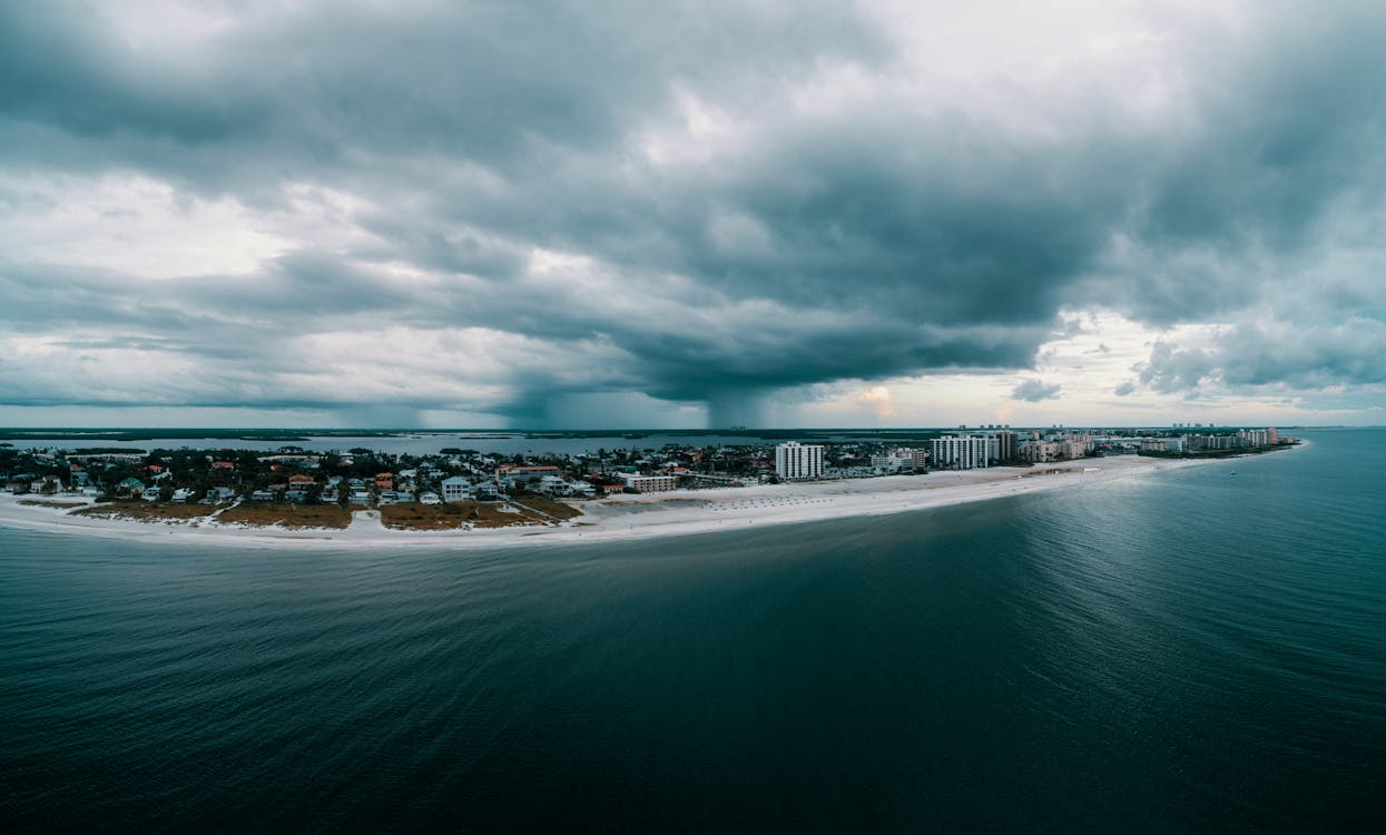 Land Surrounded by Body of Water Under White Clouds