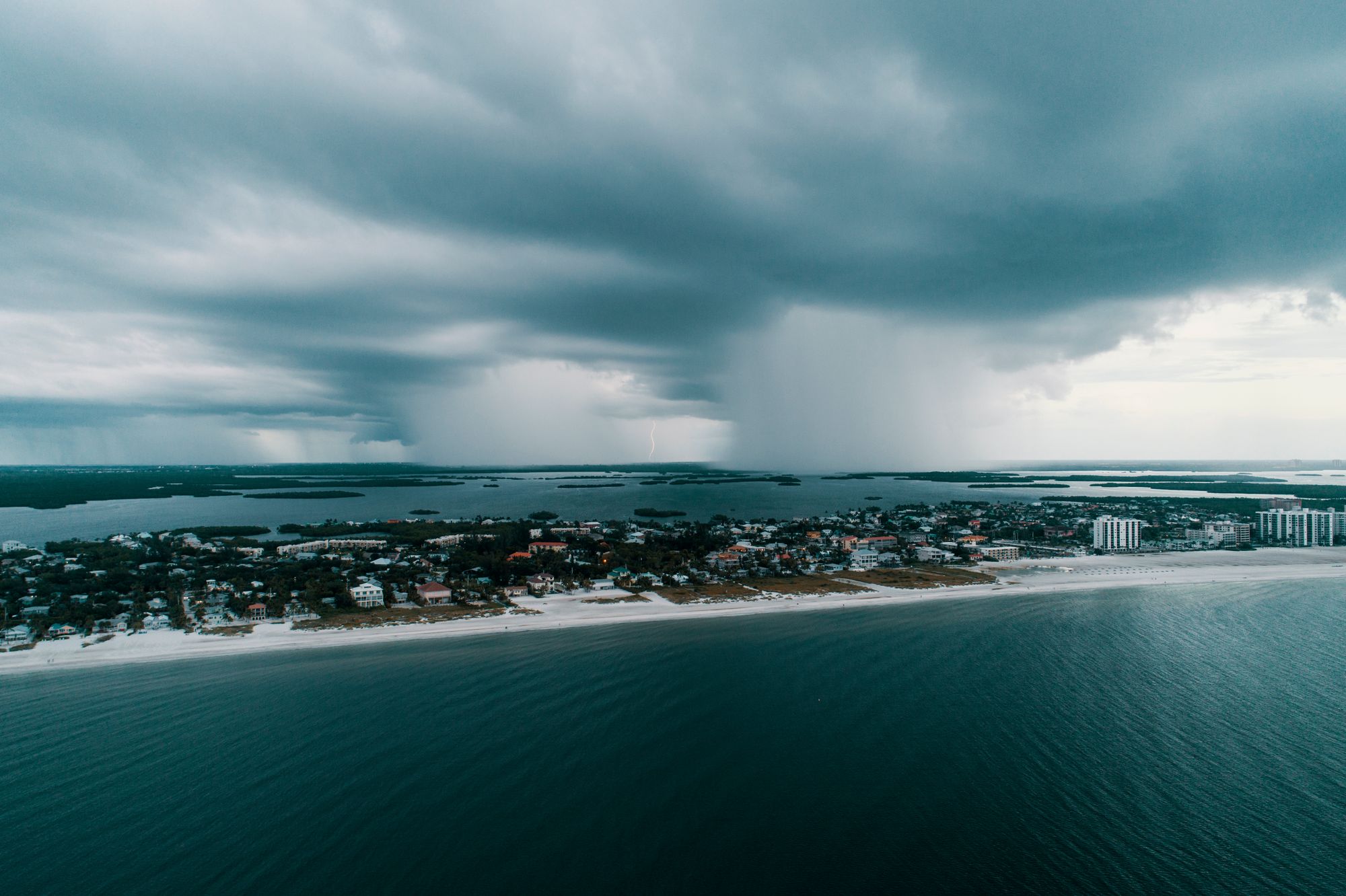 Nubes densas de tormenta sobre una costa con el mar agitado y palmeras dobladas por el viento