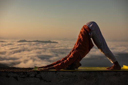 A person practicing yoga atop a mountain with a breathtaking sunrise view.