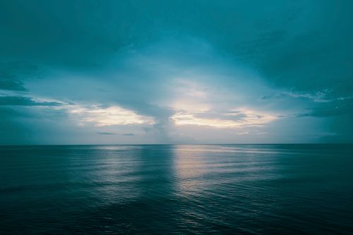 Free Serene view of the ocean at sunset with dramatic clouds and a calm horizon, perfect for nature-inspired themes. Stock Photo