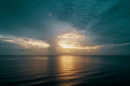 Free A breathtaking view of the sunset over a calm ocean, with vibrant colors reflecting on the water. Stock Photo