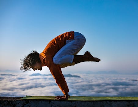 Person performing yoga on a mountain edge above the clouds.