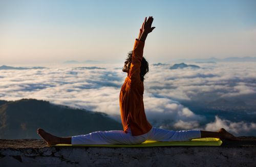 Free Serene yoga pose on a mountain edge above a sea of clouds at sunrise symbolizes mindfulness and peace. Stock Photo