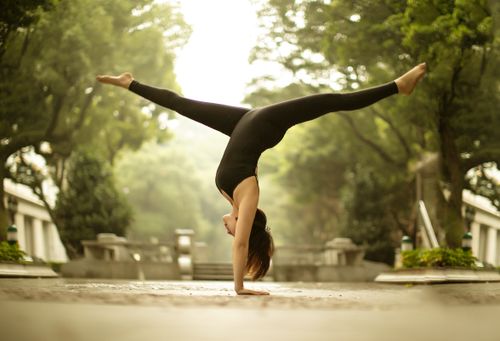 Free Woman performing a handstand in a peaceful park setting showcasing balance and fitness. Stock Photo