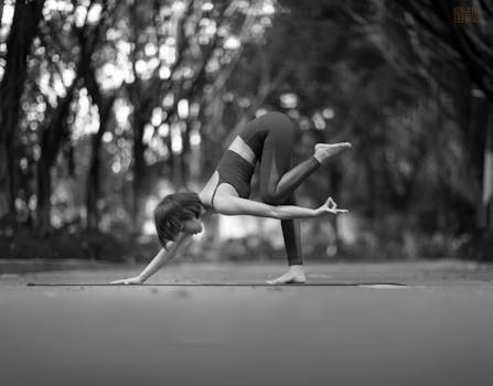 A woman practicing yoga in a park, captured in black and white.