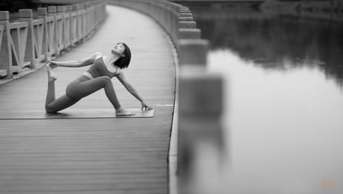 Free Woman in yoga pose on a bridge, black and white photo emphasizing tranquility. Stock Photo