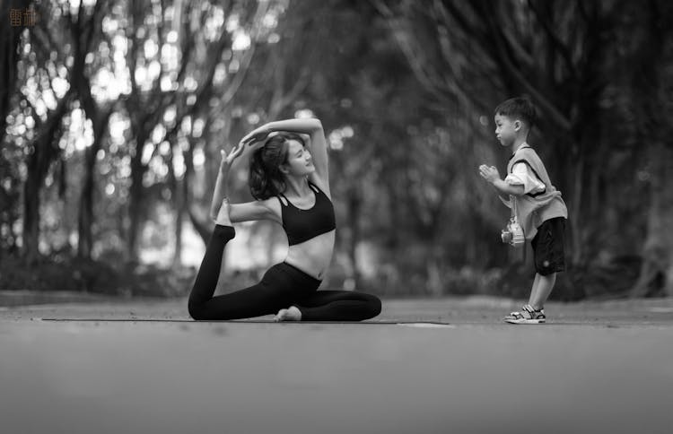 Woman Practicing Yoga With Child Outdoors