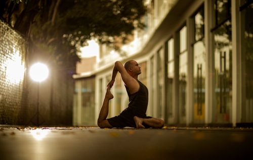 Free A man practicing a yoga pose in an urban setting, showcasing balance and flexibility. Stock Photo