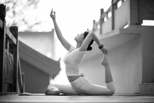 Elegant monochrome photo of a woman in a graceful yoga pose outdoors, exuding tranquility.
