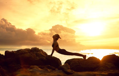 Free A Woman Doing Stretching on the Rocks Stock Photo