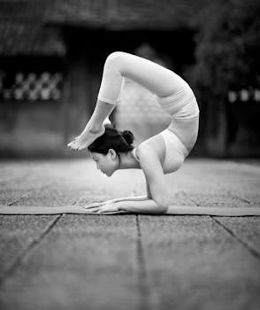Woman performing a challenging yoga pose outdoors in black and white.