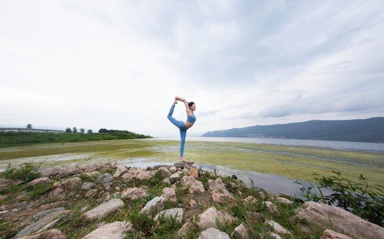 Woman Standing On One Leg On A Stack Of Rocks