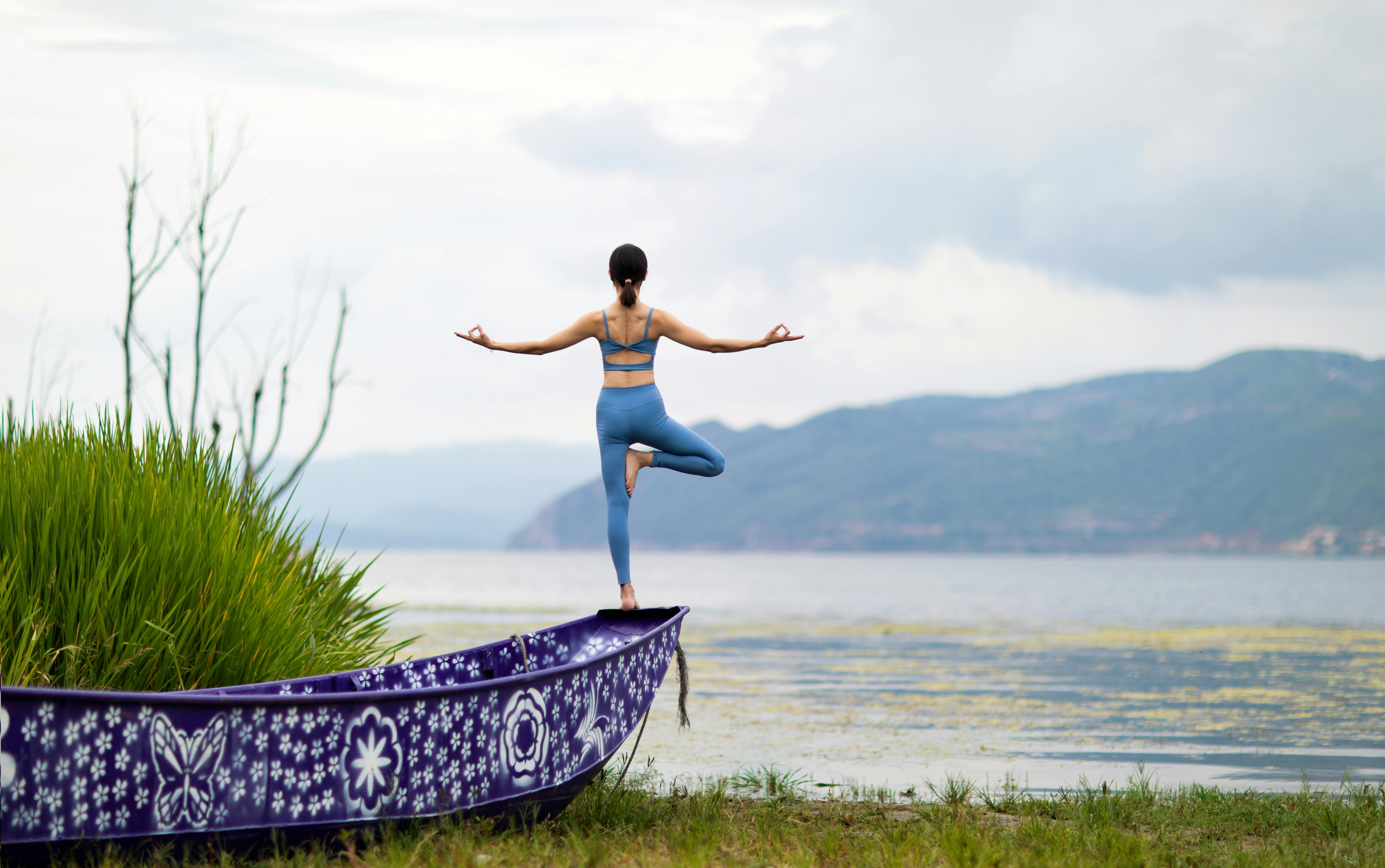 Woman Doing a Yoga Tree Pose on a Boat by a Lake · Free Stock Photo