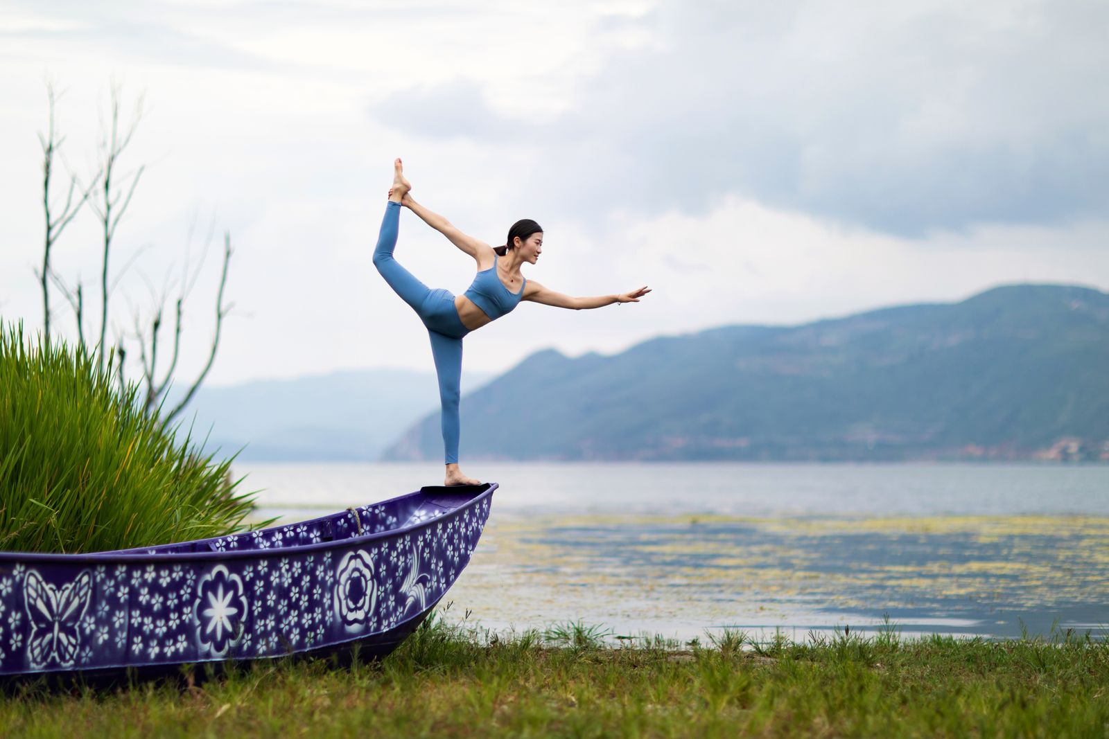 Woman balancing in Boat Pose yoga posture outdoors to strengthen abdominal muscles for a flat tummy
