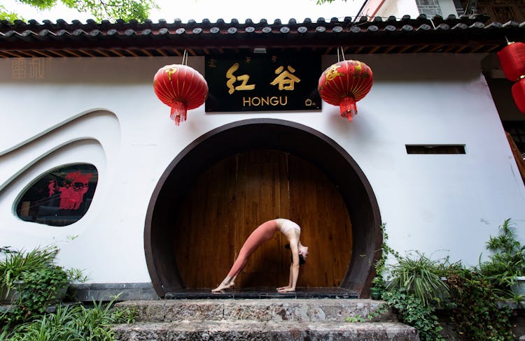 Gymnast Stretching Near Traditional House