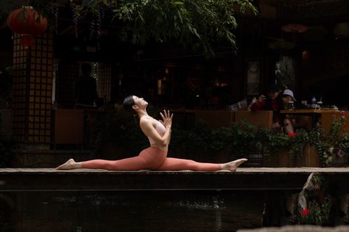 Free A woman in a yoga pose does a split on a wooden bridge, showcasing strength and flexibility in an outdoor setting. Stock Photo