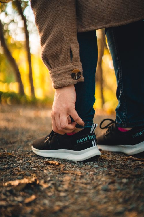 Free Close-up of a person adjusting their black sneakers during a walk in nature. Stock Photo