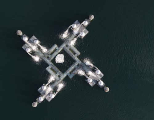 Free Aerial shot showing a geometric industrial platform over a body of water. Stock Photo